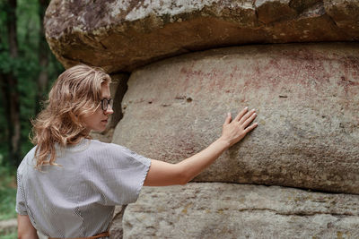 Low section of woman looking at stone wall