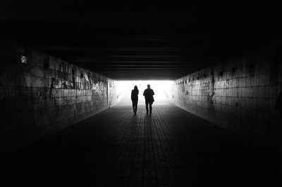 Rear view of silhouette people walking in tunnel