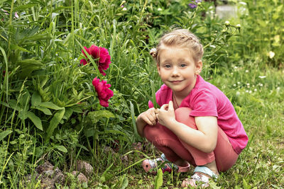 Portrait of cute girl holding pink flowers on field