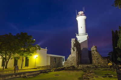 Lighthouse amidst buildings against sky at night