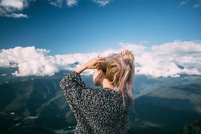 Woman tying hair against mountains