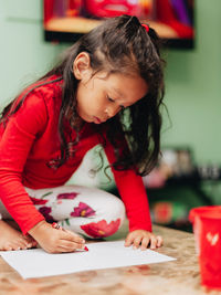 Girl looking away while sitting on table