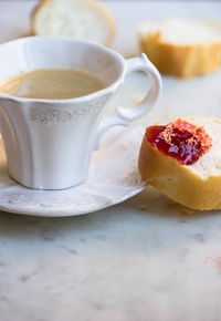 Close-up of coffee and strawberry jam on baguette