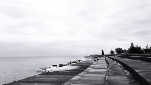 Pier on sea against cloudy sky