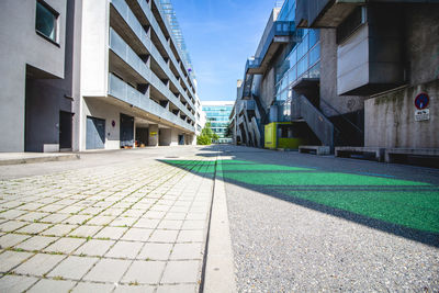 Empty footpath amidst buildings in city