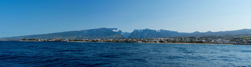 Scenic view of sea and mountains against clear blue sky