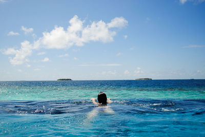 Rear view of woman in swimming pool against sea