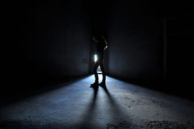 Silhouette man standing in illuminated tunnel