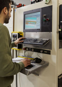 Young male carpenter operating cnc machine in workshop