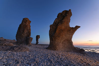 Rock formation on beach against clear sky