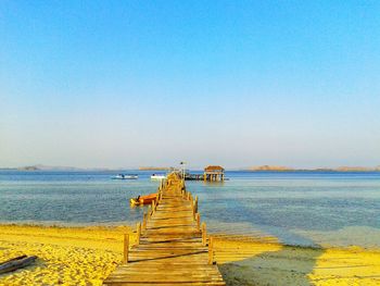 Pier over sea against clear blue sky