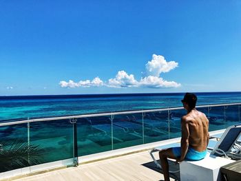 Rear view of shirtless man standing against sea