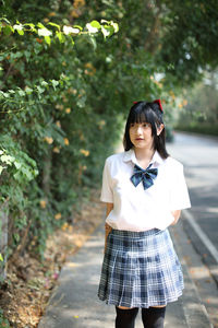 Young woman standing against tree