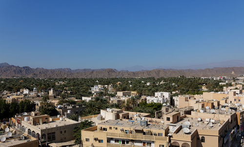 High angle view of buildings in town against clear blue sky