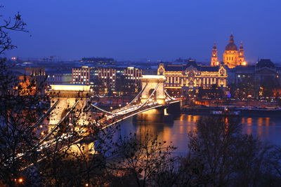 Illuminated bridge over river in city at night