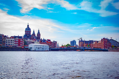 View of buildings and river against cloudy sky