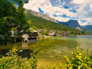 Scenic view of lake by buildings and mountains against sky