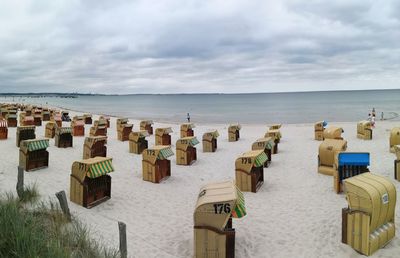 Hooded chairs on beach against sky