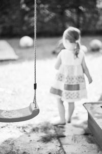 Close-up of swing with girl in background at park