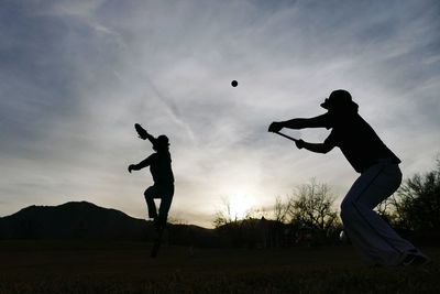 Silhouette boys playing baseball at sunset