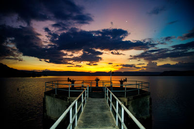 Pier over sea against sky during sunset