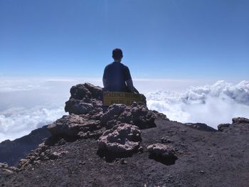 Rear view of man sitting on mountain