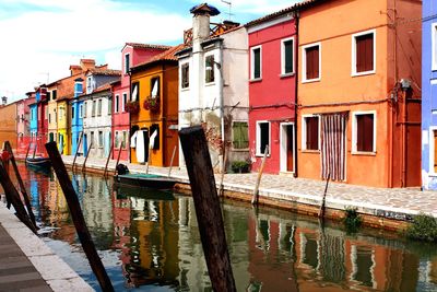 Canal amidst houses against sky in city