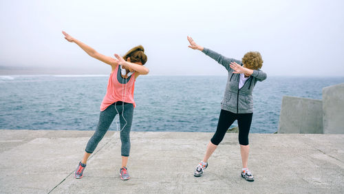 Mother and daughter standing on pier against sky