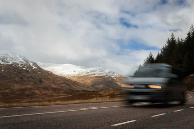 Blurred motion of road by mountain against sky