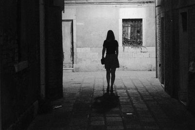 Rear view of woman walking in front of building