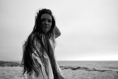 Portrait of woman at beach against sky