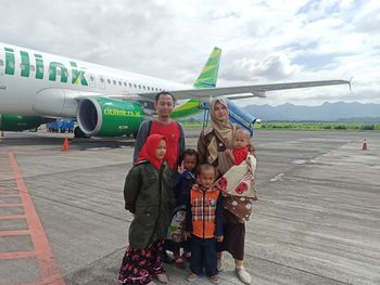 People standing on airport runway against sky