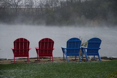 Empty chairs on beach against trees