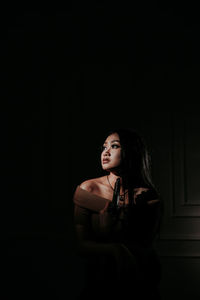 Young woman standing against black background