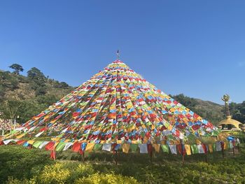 Multi colored umbrellas by trees against clear sky