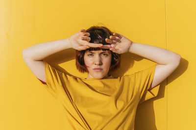 Portrait of young woman against yellow wall