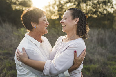 Close up portrait of adult mother and daughter embracing and laughing