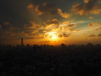 Cityscape against cloudy sky during sunset