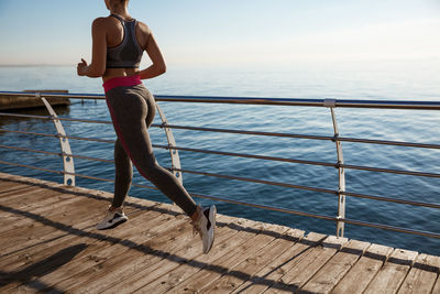 Full length of woman running by railing against sea