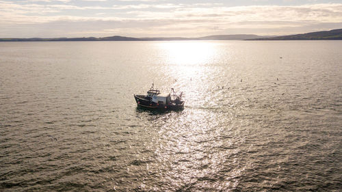 Boat sailing in sea against sky during sunset