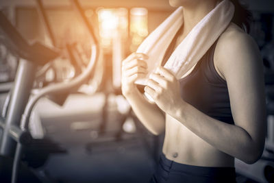 Midsection of woman with towel standing in gym