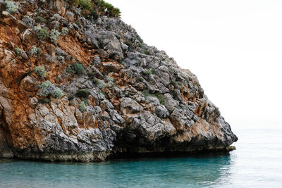 Rock formations by sea against clear sky