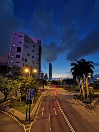 Road by illuminated buildings against sky