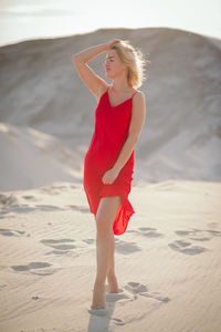 Portrait of young woman standing on sand at beach