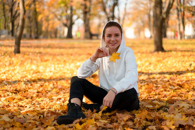 Portrait of smiling woman sitting on autumn leaves