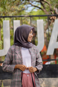 Portrait of a hijab muslim student in front of a park