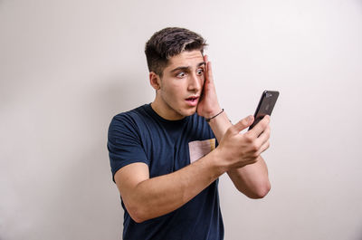 Young man using mobile phone against white background