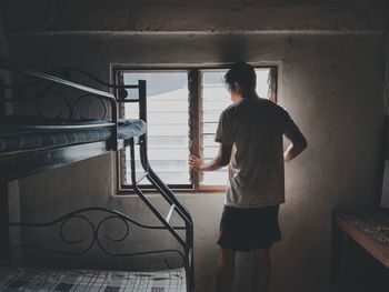 Rear view of man standing against window in building