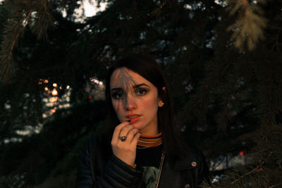 Portrait of beautiful young woman against trees