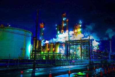 Illuminated factory against sky at night